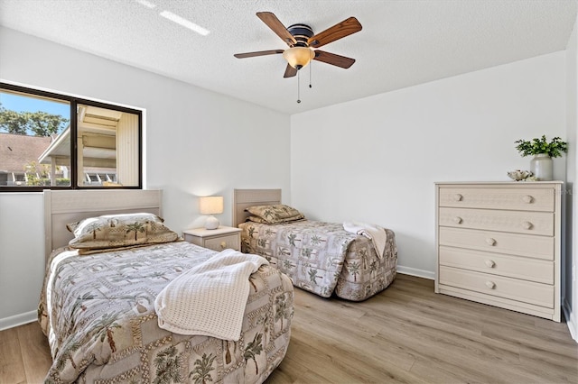 bedroom with a ceiling fan, wood finished floors, and a textured ceiling