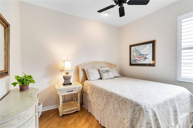bedroom featuring baseboards, multiple windows, a ceiling fan, and light wood-type flooring