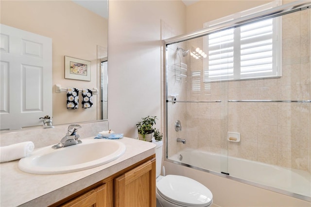 bathroom with toilet, enclosed tub / shower combo, and vanity