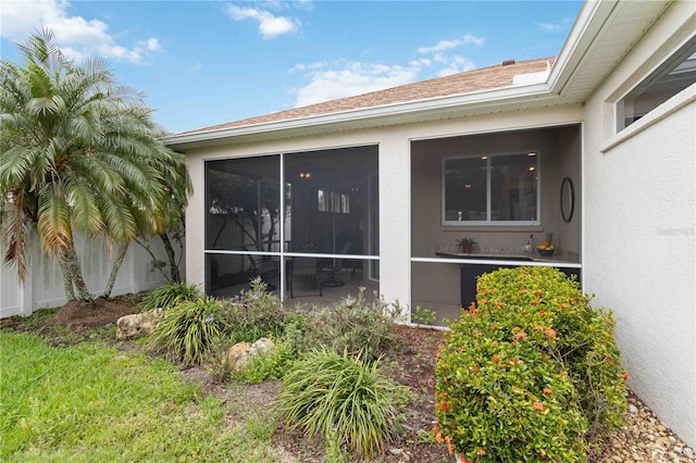 view of side of home featuring a sunroom and stucco siding