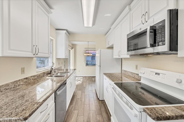 2267 Pueblo Ln Unit V40, Sarasota, FL 34231 - kitchen with stainless steel appliances, wood tiled floors, white cabinets, a sink, and light stone counters