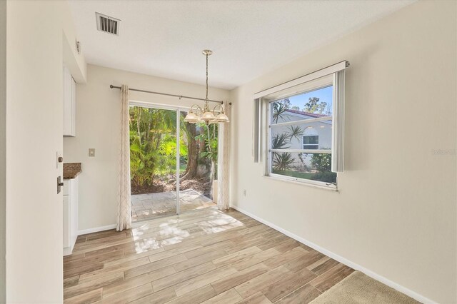 2267 Pueblo Ln Unit V40, Sarasota, FL 34231 - unfurnished dining area with a chandelier, light wood-style flooring, baseboards, and plenty of natural light