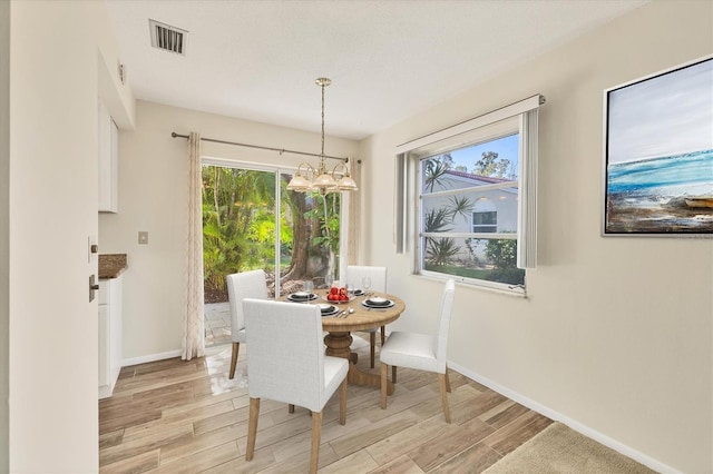 2267 Pueblo Ln Unit V40, Sarasota, FL 34231 - dining area featuring a chandelier, light wood-type flooring, and baseboards
