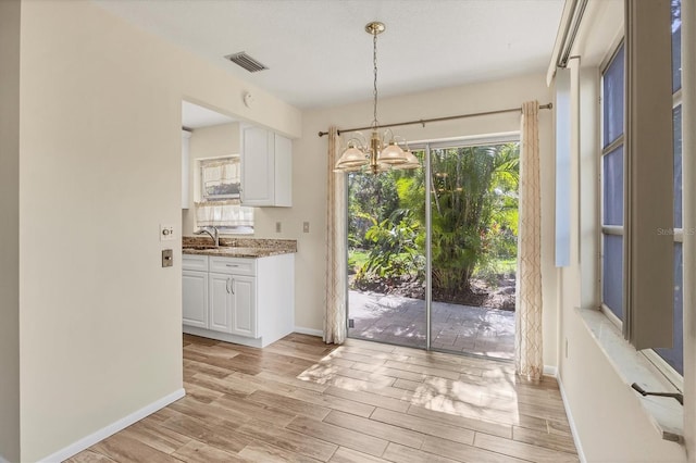 2267 Pueblo Ln Unit V40, Sarasota, FL 34231 - kitchen featuring a sink, white cabinets, a chandelier, and light wood-type flooring