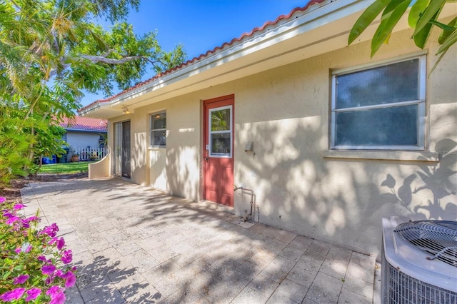 2267 Pueblo Ln Unit V40, Sarasota, FL 34231 - entrance to property with a patio area, stucco siding, a tiled roof, and central AC unit