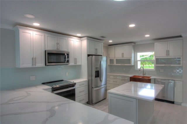 306 Island Cir, Sarasota, FL 34242 - kitchen featuring a sink, recessed lighting, stainless steel appliances, backsplash, and light stone counters