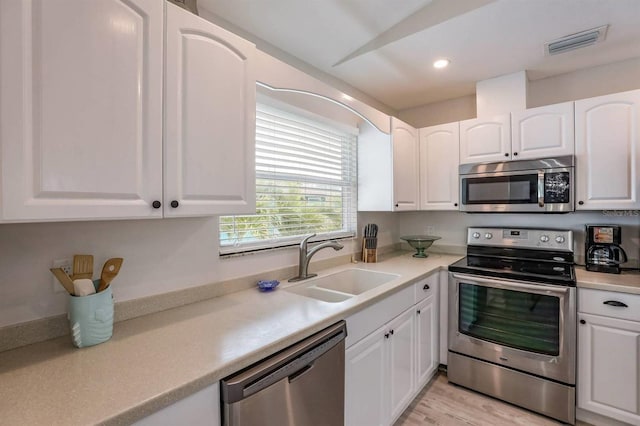 kitchen with visible vents, white cabinets, a sink, light countertops, and appliances with stainless steel finishes