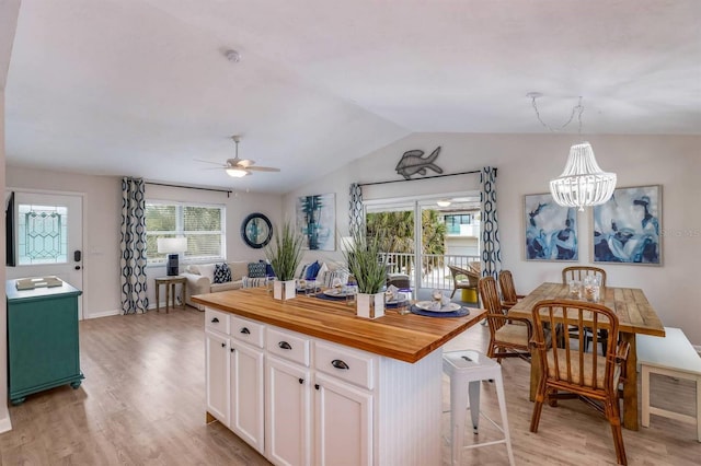 kitchen featuring white cabinets, butcher block countertops, lofted ceiling, and light wood finished floors