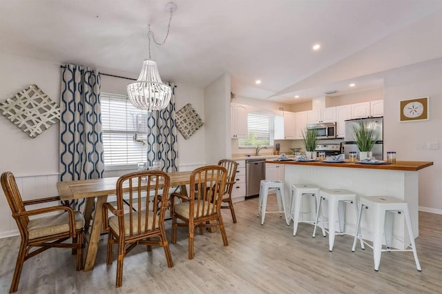 dining area featuring recessed lighting, light wood finished floors, vaulted ceiling, and an inviting chandelier