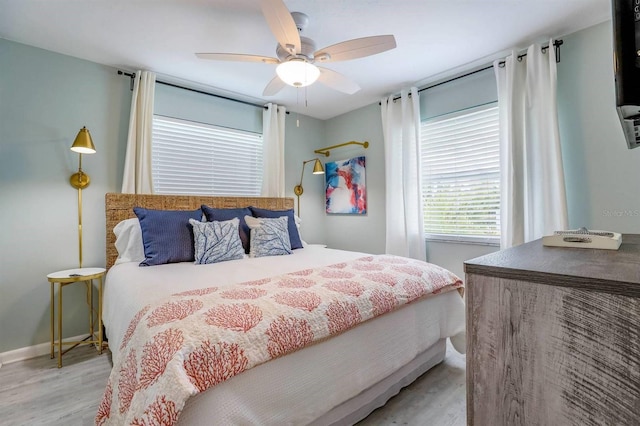 bedroom with light wood-type flooring, baseboards, and a ceiling fan