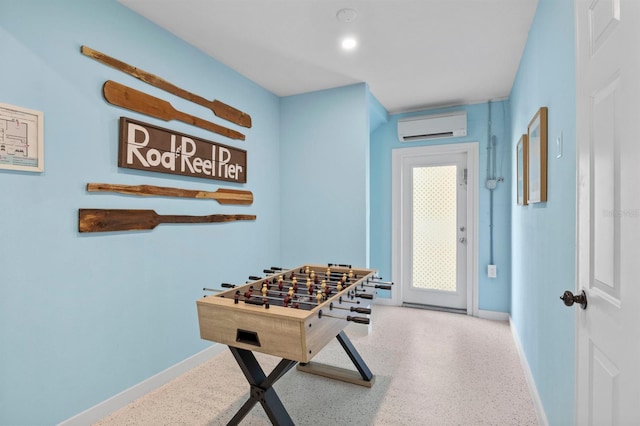 game room with speckled floor, baseboards, and a wall mounted AC