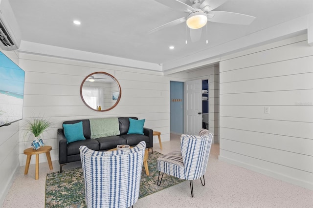 living area with speckled floor, a ceiling fan, recessed lighting, wood walls, and a wall mounted air conditioner