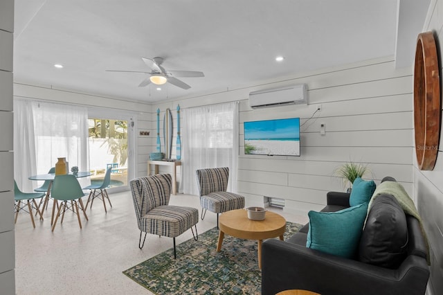 living room featuring a ceiling fan, speckled floor, an AC wall unit, and recessed lighting