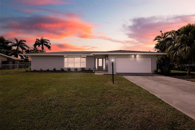 mid-century home with an attached garage, concrete driveway, fence, stucco siding, and a front lawn