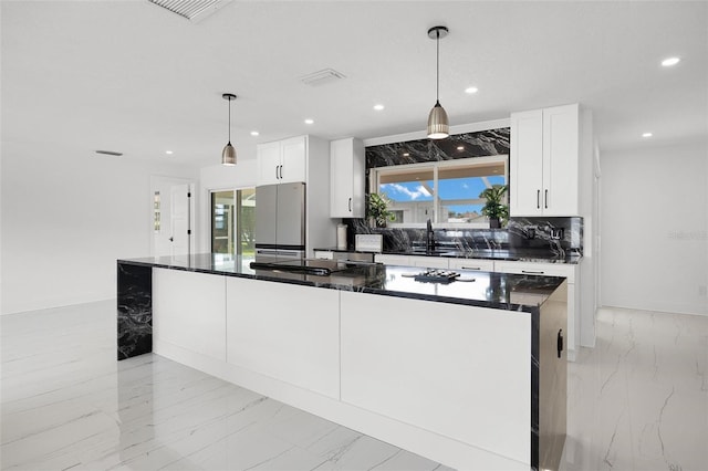 kitchen with recessed lighting, marble finish floor, freestanding refrigerator, and stovetop