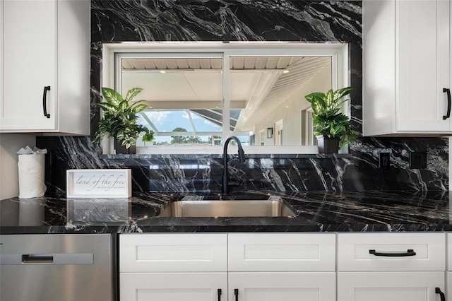 kitchen with a sink, decorative backsplash, white cabinetry, and dark stone countertops