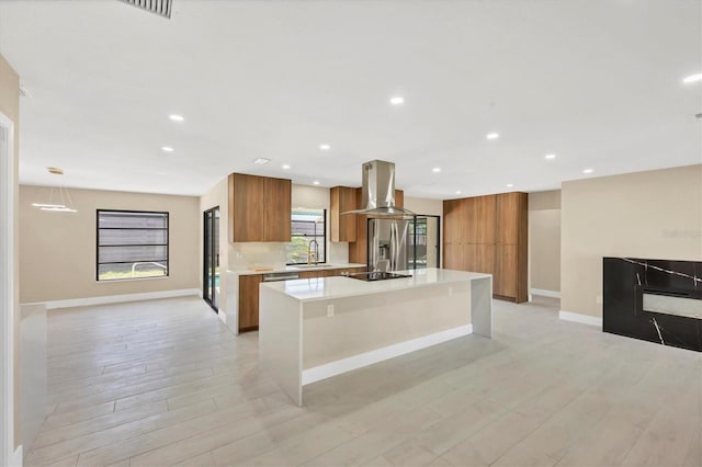 kitchen featuring island range hood, brown cabinets, modern cabinets, and a sink