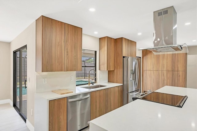 kitchen with island exhaust hood, modern cabinets, stainless steel appliances, and a sink