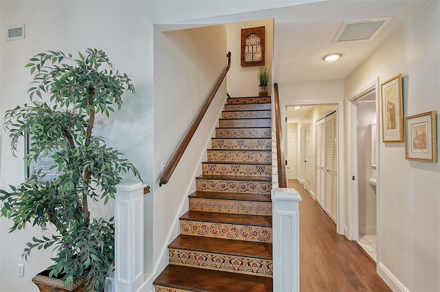 staircase with baseboards, wood finished floors, and visible vents