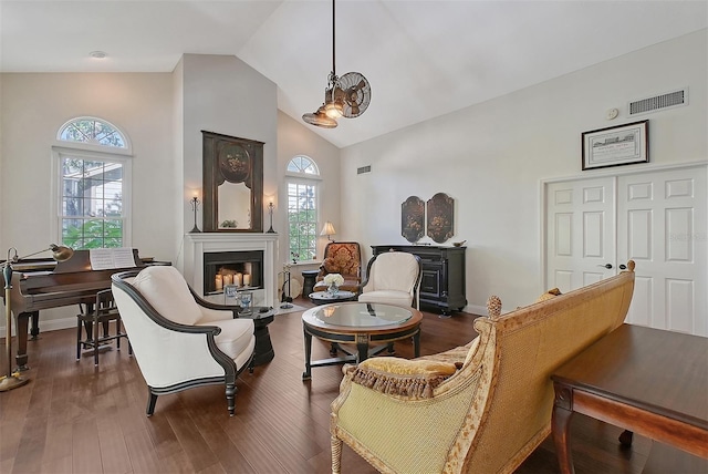 living area featuring a glass covered fireplace, visible vents, high vaulted ceiling, and a wealth of natural light