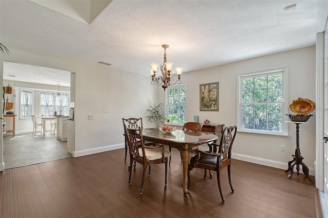 dining area featuring a chandelier, plenty of natural light, and dark wood-style floors