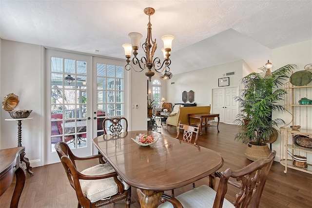 dining space with a notable chandelier, french doors, and wood finished floors