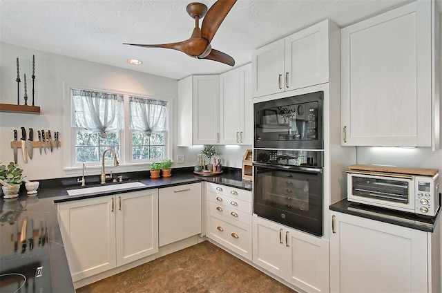 kitchen with white cabinets, dark countertops, a sink, and black appliances