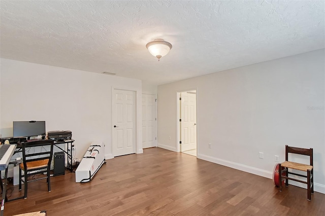 interior space featuring wood finished floors, a textured ceiling, and baseboards