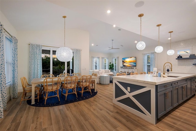 kitchen featuring a sink, wood finished floors, decorative light fixtures, and vaulted ceiling