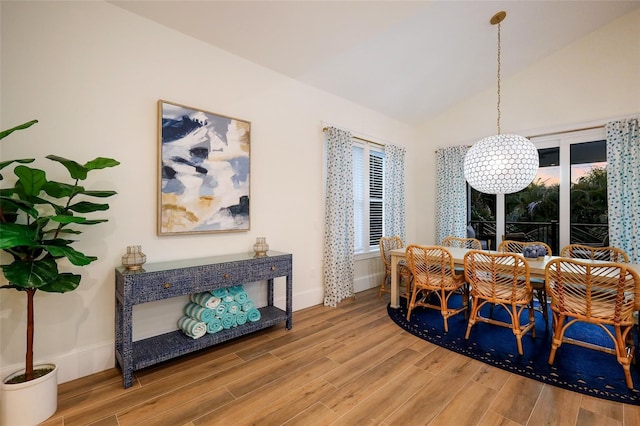 dining area with lofted ceiling, baseboards, and wood finished floors