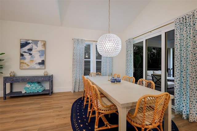 dining area featuring baseboards, vaulted ceiling, and wood finished floors