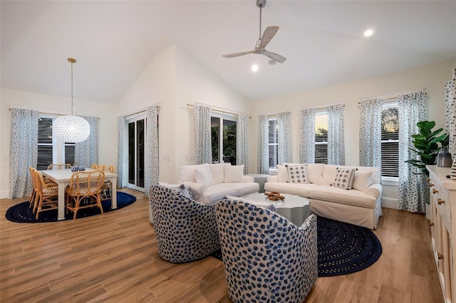 living area featuring recessed lighting, light wood-style flooring, ceiling fan with notable chandelier, and lofted ceiling
