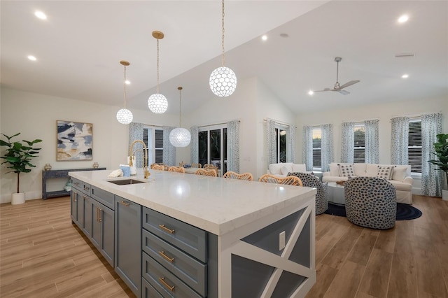 kitchen with a sink, open floor plan, ceiling fan, light countertops, and gray cabinets