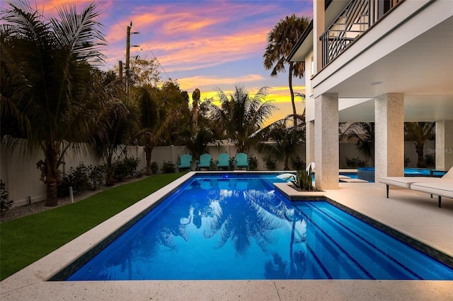 pool at dusk with a fenced in pool, a patio area, and a fenced backyard
