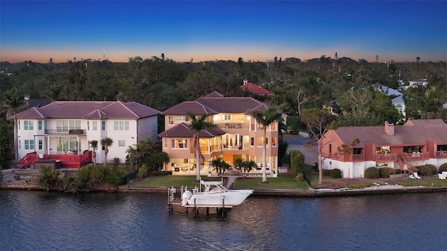 aerial view at dusk featuring a residential view and a water view