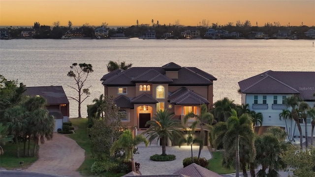 view of front of house with a tiled roof, a water view, and stucco siding