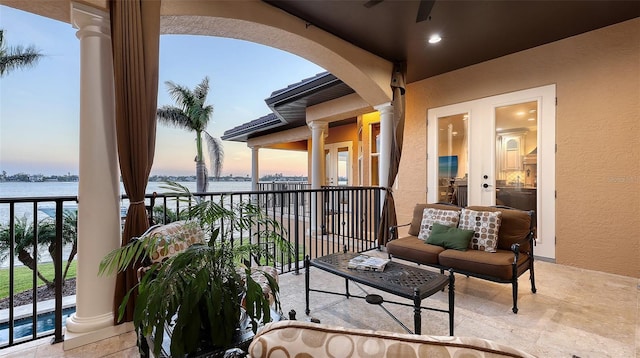 balcony featuring a water view and ceiling fan