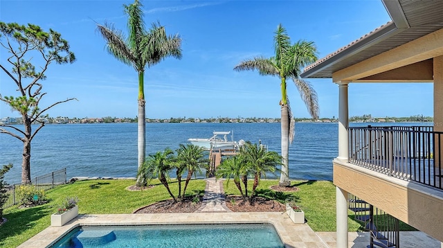 pool featuring a yard, a water view, and fence