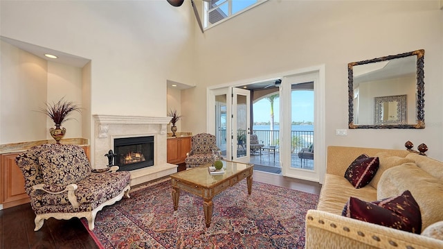living area with a high end fireplace, a ceiling fan, and dark wood-style flooring