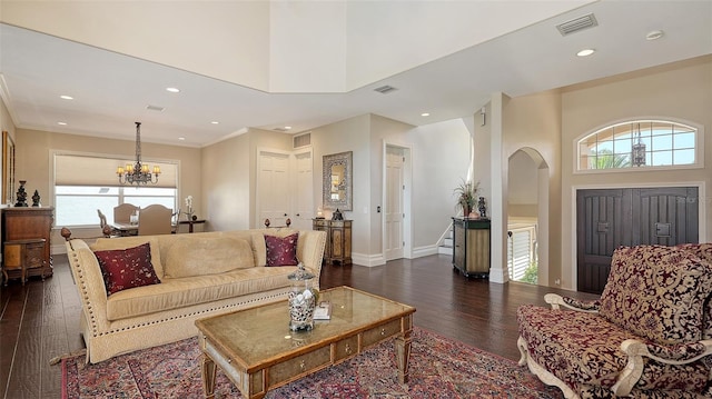 living room with visible vents, arched walkways, dark wood-type flooring, and a chandelier