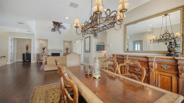 dining area with visible vents, dark wood-style floors, ceiling fan with notable chandelier, and a fireplace