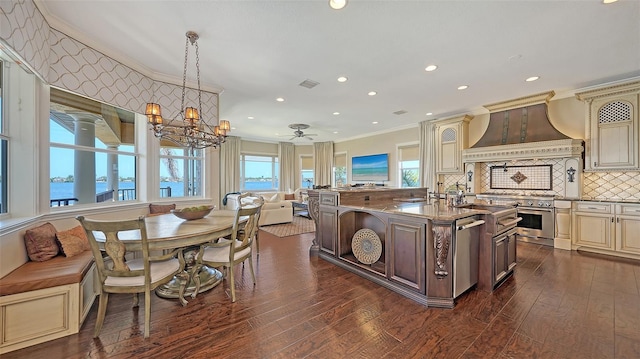 kitchen with premium range hood, dark wood-style floors, ornamental molding, stainless steel appliances, and cream cabinetry