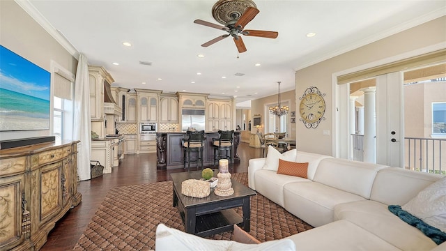 living area featuring crown molding, a wealth of natural light, ceiling fan with notable chandelier, and dark wood-type flooring