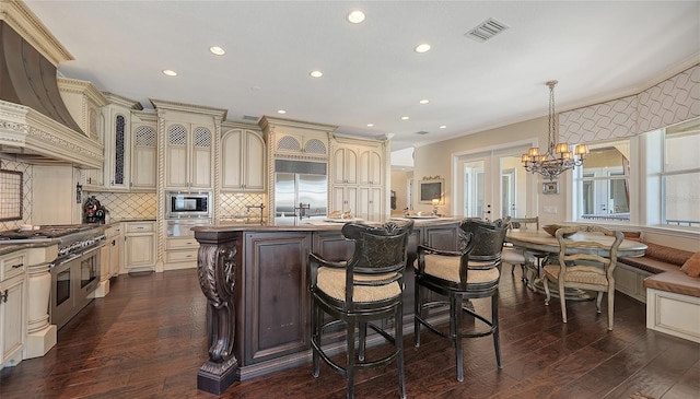 kitchen featuring a warming drawer, visible vents, cream cabinets, custom exhaust hood, and built in appliances
