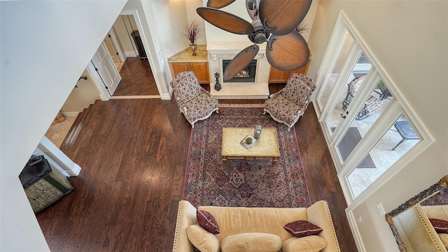 living room featuring a towering ceiling, dark wood-style flooring, baseboards, and a tile fireplace