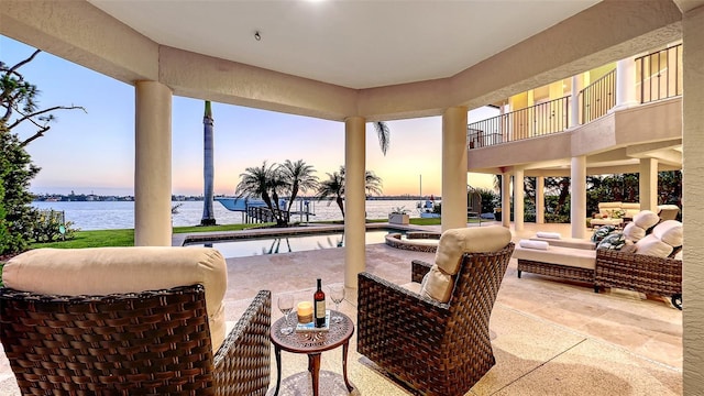 patio terrace at dusk featuring a water view, outdoor lounge area, and an outdoor pool