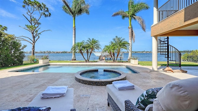 view of pool featuring stairs, a water view, a pool with connected hot tub, and a patio