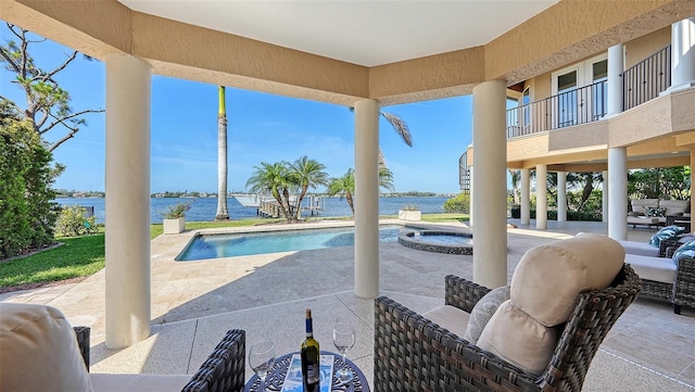 view of patio with a water view and a pool with connected hot tub