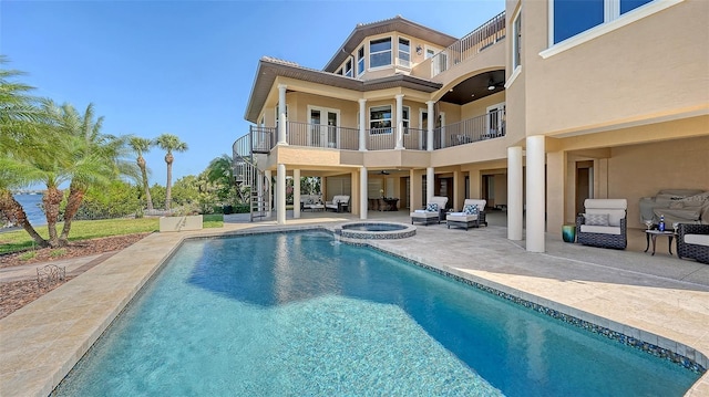 back of house featuring stairway, stucco siding, a balcony, and an outdoor hangout area