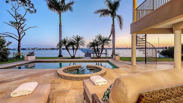 view of swimming pool with stairs, a water view, a pool with connected hot tub, and a patio